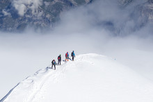 Tied Climbers Climbing Mountain With Snow Field Tied With A Rope With Ice Axes And Helmets