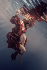 Wall Mural - Girl in a red dress under water