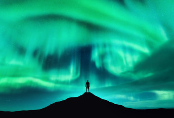 aurora borealis and silhouette of a man on the mountain peak. lofoten islands, norway. beautiful aur