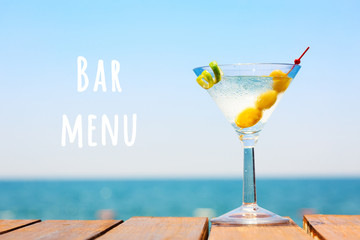 Wall Mural - Glass of martini bianco at the wooden pier. Concept of summer vacation. Popular cocktail by the sea. Vacation background. Horizontal. Bar menu wording