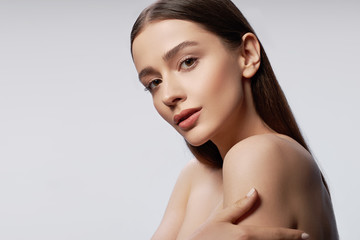 young pretty lady with natural makeup posing against light gray background