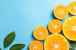 Sliced orange fruits with leaves on blue background, flat design