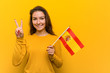 © Asier - Young european woman holding a spanish flag showing number two with fingers.