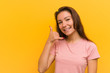 © Asier - Young european woman isolated over yellow background showing a mobile phone call gesture with fingers.