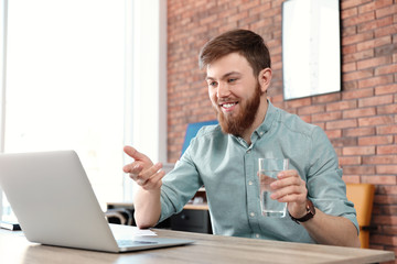 Wall Mural - Young man using video chat on laptop in home office