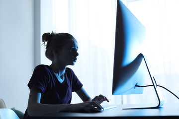 Shocked teenage girl using computer at table indoors. Danger of internet