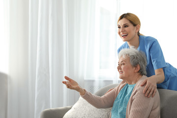 Wall Mural - Nurse with elderly woman indoors, space for text. Assisting senior people