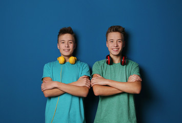 Canvas Print - Teenage twin brothers with headphones on color background