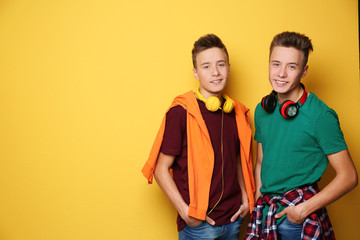 Canvas Print - Teenage twin brothers with headphones on color background. Space for text