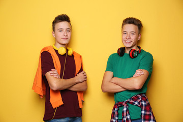 Canvas Print - Teenage twin brothers with headphones on color background