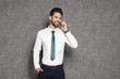 © New Africa - Portrait of businessman talking on phone against grey background