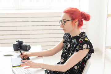 Business, designer and animator concept - young woman illustrator or artist with pink hair draws on the graphic tablet