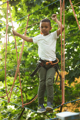 Sticker - Little African-American boy climbing in adventure park. Summer camp