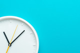 Part of white wall clock with yellow second hand hanging on wall. Close up image of plastic wall clock over turquiose blue background with copy space. Photo of time management or time is going concept