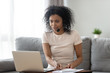 © fizkes - Young african woman wearing headset looking at laptop making notes