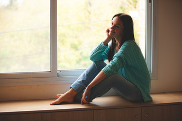 Wall Mural - woman sitting on the window sill