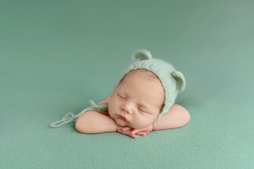 sleeping newborn baby on a green background. photoshoot for the newborn. a few days from birth.
