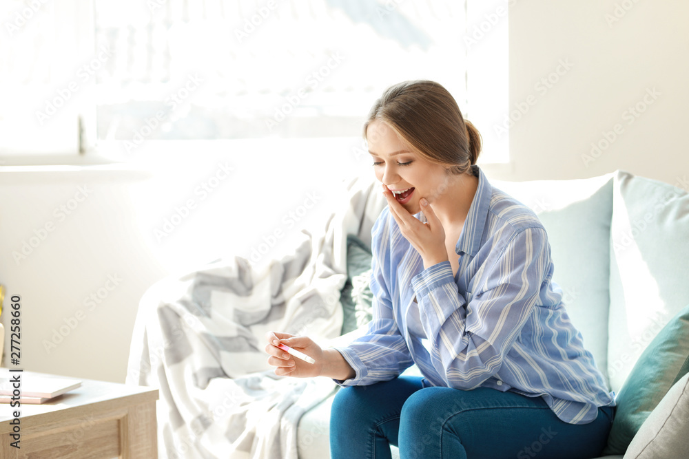 Happy young woman with pregnancy test at home