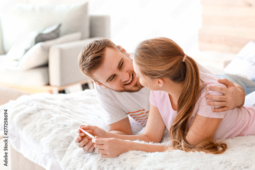 Happy couple with pregnancy test at home