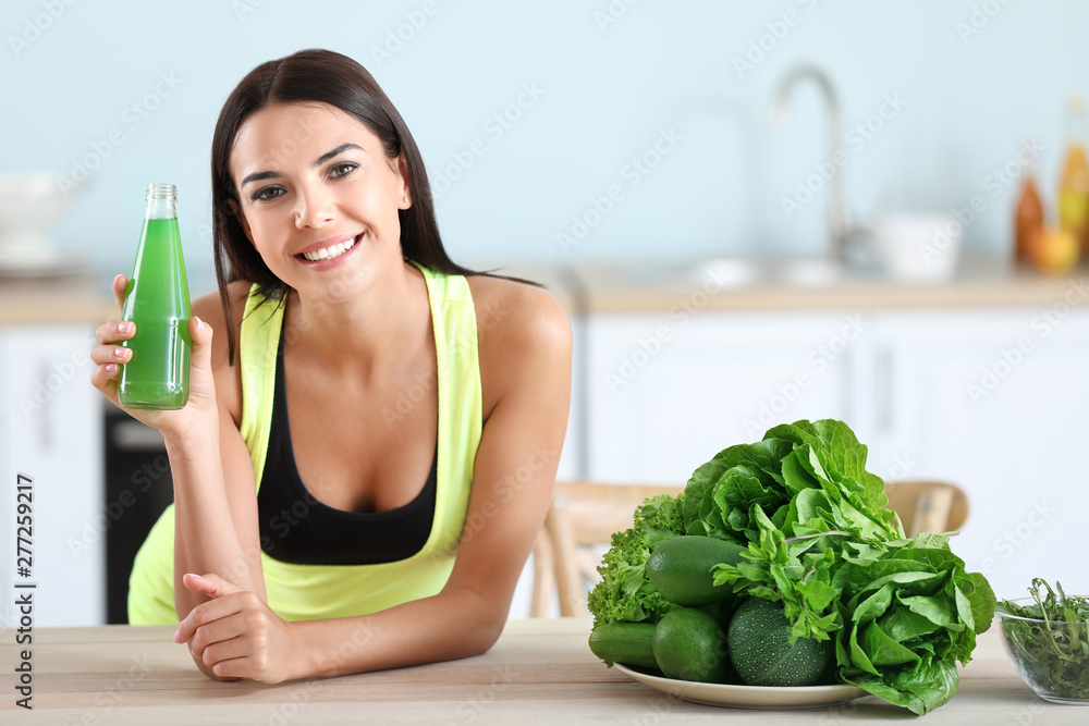 Young woman with healthy vegetable juice in kitchen