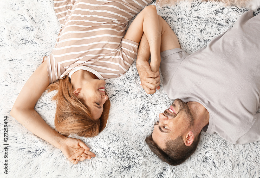 Happy couple in love lying on bed, top view