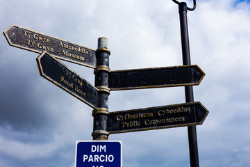 Road sign on the crossroads with blue cloudy sky in the background.