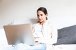 © dianagrytsku - Young woman using laptop computer smiling happy watching and browsing or doing online internet shopping at home modern living room