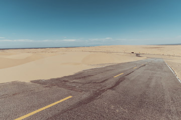 Wall Mural - a road in the middle of the sand dunes in the desert.