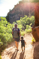 Mother and child hiking together along a scenic mountain trail on a summer day. Lifestyle photo of people outdoors enjoying nature and being active