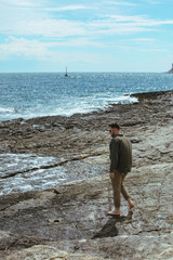 Wall Mural - man walking by rocky beach in windy day summer vacation. enjoy sea view