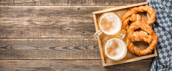 Fresh beer and pretzels on wooden table