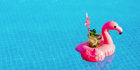 Fresh coctail mojito on inflatable pink flamingo toy at swimming pool. Vacation concept.