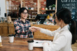 © PR Image Factory - two seated asian women shaking hands in coffee shop smiling. hr lady manager welcome new employee to team after interview in cafe bar. female freelancers in glasses handshaking closing deal meeting