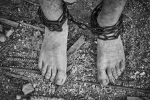 Close-up Shot Of Barefoot Legs Tied Up With Old Chain