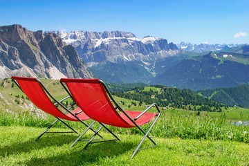 Two red relaxing chairs and beautiful panorama of summer Alps mountain