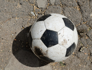 Old soccer black and white ball on asphalt