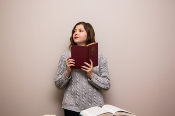 Wall Mural - Portrait of young brunette woman with book in her hand