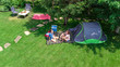 © Iuliia Sokolovska - Aerial top view of campsite from above, mother and daughter having fun, tent and camping equipment under tree, family vacation in camp outdoors concept