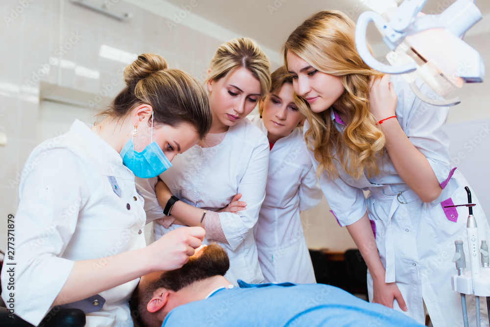 Medical University. Professional teacher dentist doctor treats teeth to the patient in the office on modern equipment. The concept of medical training and transfer of experience.