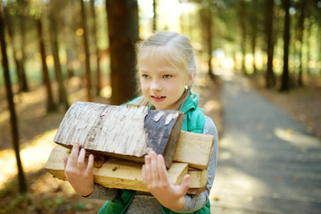 Wall Mural - adorable young girl carrying tree logs to a bonfire. child having fun at camp fire. camping with chi