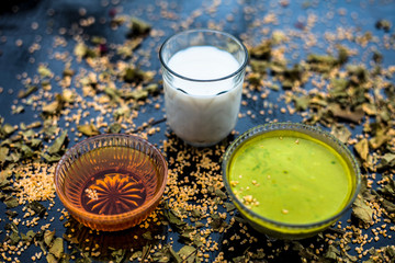 Neem or Indian Lilac face mask on the black wooden surface for Anti-aging benefits of neem leaves paste, oatmeal, milk, and honey.