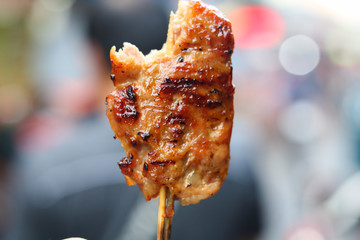 Holding asian delicious spicy street food grilled meat on stick with sauce in Ho Chi Minh, Vietnam