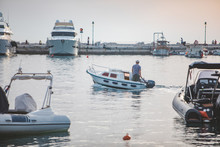 Man On Small Motor Boat In City Harbor Dock
