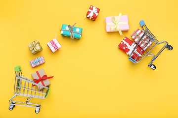 Wall Mural - Small shopping carts with gift boxes on yellow background