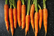 Young Carrot With Tops In Row Over Black Texture Background. Flat Lay, Space. Cooking Concept, Food Background.