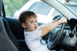 Little boy smiling holding the wheel of the car.child boy is playing in the front seat of the  car and smiles sincerely