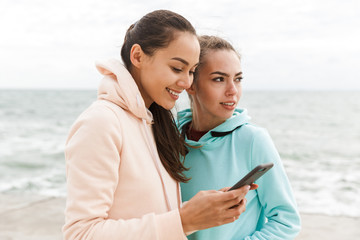 Wall Mural - Two pretty smiling fitness women wearing hoodies