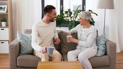 Sticker - family, generation and people concept - happy smiling adult son and senior mother drinking coffee at home