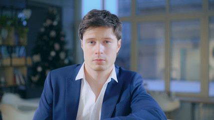 Poster - Portrait caucasian fashionable businessman looking at the camera sitting in the office. Adult male wearing in casual blue jacket.