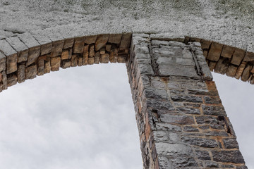 Wall Mural - Backlight on stone and brick open archways against gray sky, horizontal aspect